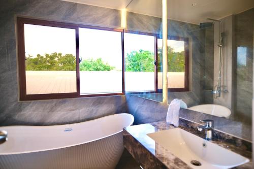 a bathroom with a tub and a sink and windows at KHAMI HOUSE Resort in Panglao Island