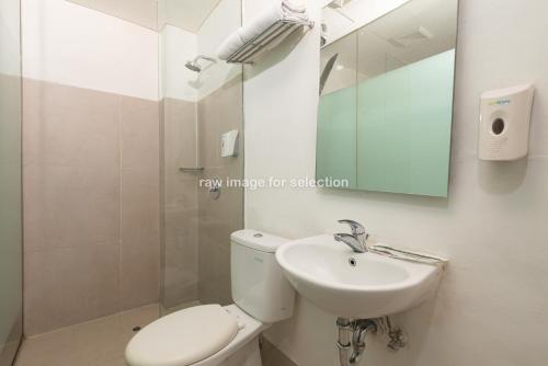 a bathroom with a toilet and a sink and a mirror at Whiz Hotel Falatehan Jakarta in Jakarta
