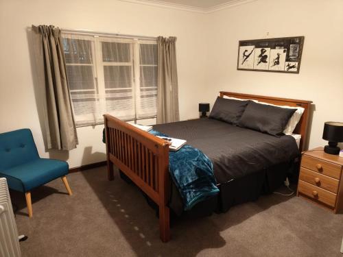 a bedroom with a bed and a blue chair at Larsen Apartment in Palmerston North