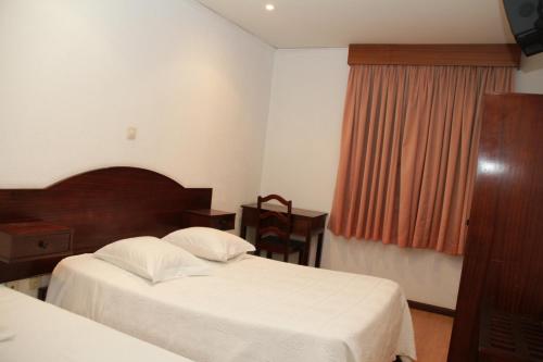 a hotel room with two beds and two lamps at Residencial Bela Star in Porto