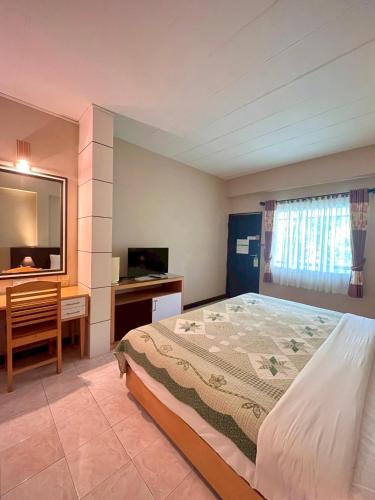 a bedroom with a bed and a desk and a television at Rommai Greenpark in Lampang