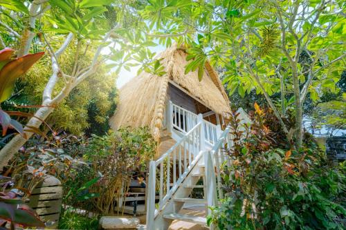 a thatch roofed house with a staircase leading to it at Hai Tide Beach Resort in Nusa Lembongan