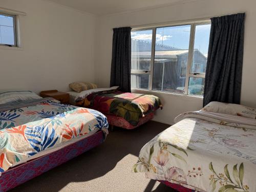 a bedroom with two beds and a window at Mount Holiday Home in Tauranga