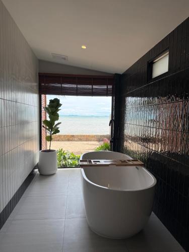 a bath tub in a bathroom with a view of the ocean at Boon Heritage House Koh Samui in Koh Samui
