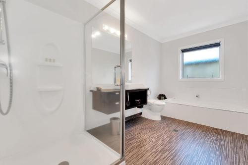 a white bathroom with a shower and a toilet at Matamata Central Motel in Matamata