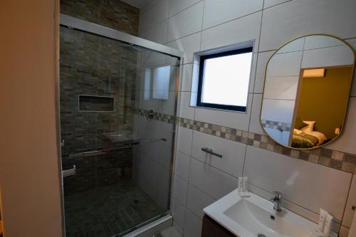 a bathroom with a shower and a sink and a mirror at Weavers Nest Guesthouse in Modimolle