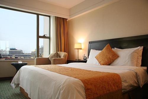 a hotel room with a bed and a large window at Ningbo Portman Plaza Hotel in Ningbo