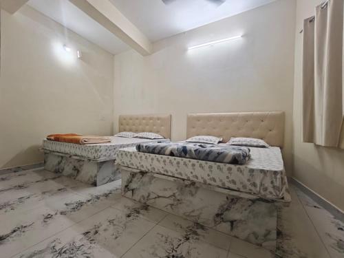 two beds in a room with white walls at Kalpavrukksha Luxury Service Apartment- Unit 4 - 1 BHK 2 King Size Cot Setup in Chikmagalūr