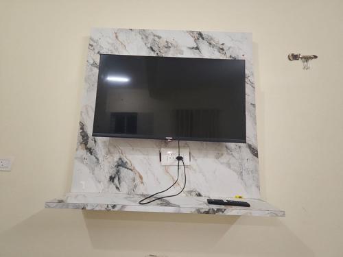 a flat screen tv hanging on a marble wall at Kalpavrukksha Luxury Service Apartment- Unit 4 - 1 BHK 2 King Size Cot Setup in Chikmagalūr