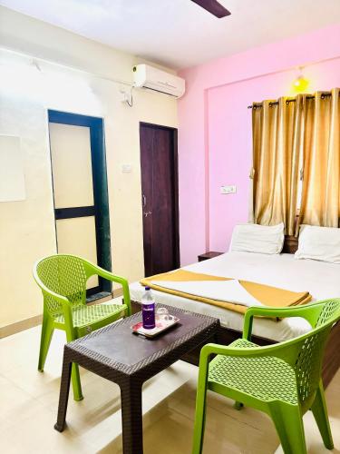 a room with a bed and two chairs and a table at Hotel Laxmi in Hinjewadi