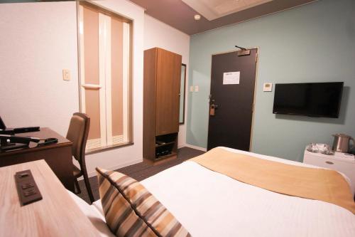 a bedroom with a bed and a desk and a television at Hotel AreaOne Nobeoka in Nobeoka