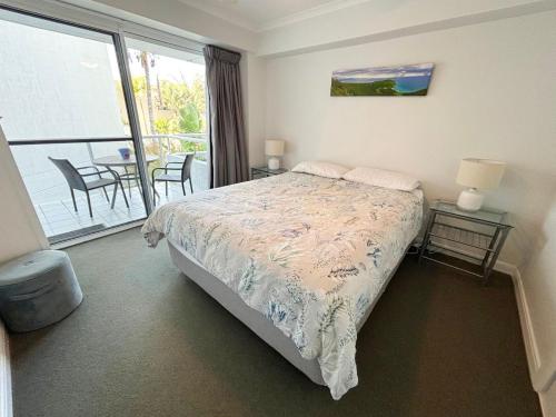 a bedroom with a bed and a balcony with a table at Ocean Shores Apartment 14 - Bring your own linen. in South West Rocks