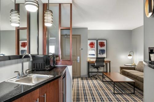 a kitchen with a sink and a living room with a couch at AmericInn by Wyndham Fairfield in Fairfield