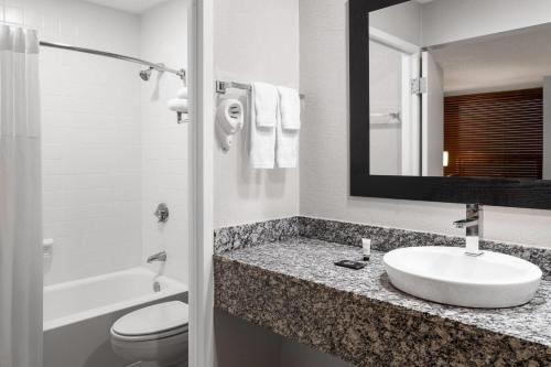 a bathroom with a sink and a toilet and a mirror at Baymont by Wyndham Great Falls City Center in Great Falls