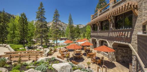 an outdoor patio with tables and umbrellas in front of a building at Everline Resort and Spa, Lake Tahoe in Olympic Valley