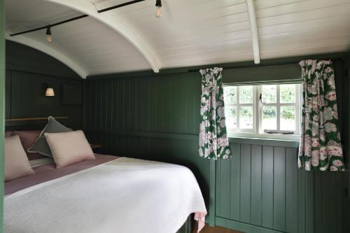 a green bedroom with a bed and a window at Hornbeam Holt in Broadway