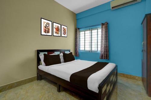 a bedroom with a bed with blue walls and a window at Hotel O Abbigere Lakeview Bangalore Formerly Shree Venkateshwar Atithi Comforts in Chik Bānavar