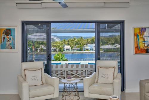 a living room with two chairs and a view of the water at Villa Aura - Private Pool - Lakefront & Near Beach in Trinity Beach