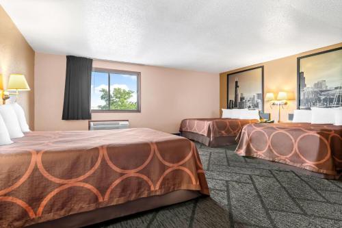 ein Hotelzimmer mit zwei Betten und einem Fenster in der Unterkunft Super 8 by Wyndham Bourbonnais/Kankakee Area in Bourbonnais