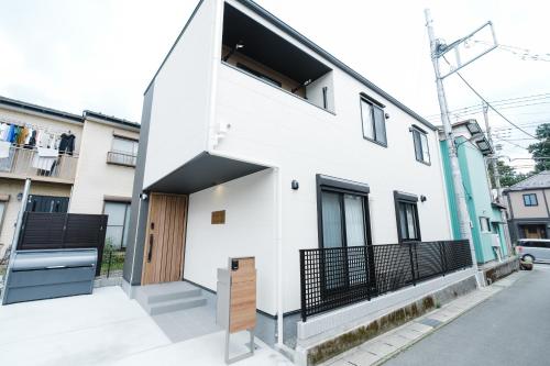 a white house with a black gate at Crescout Toa 1 in Gotemba