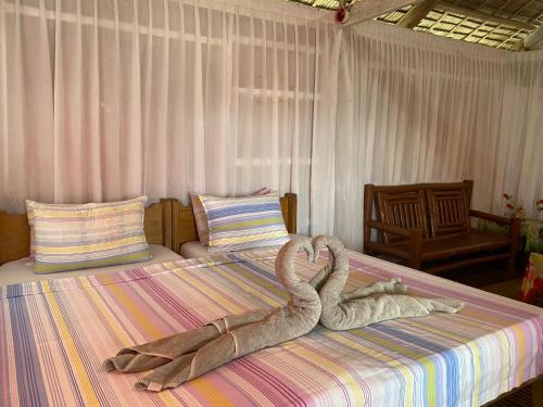 two towel swans are laying on a bed at Beachaus Resort in Pandan
