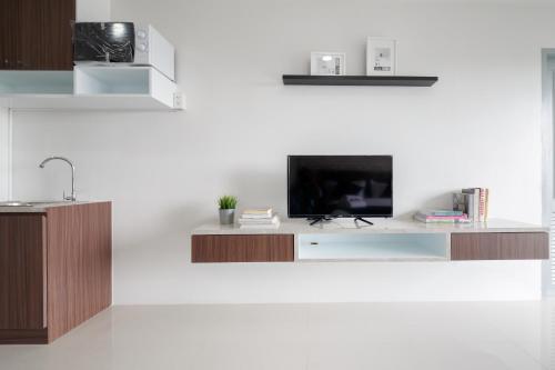 a living room with a tv on a white wall at Q Space Residence in Bangkok