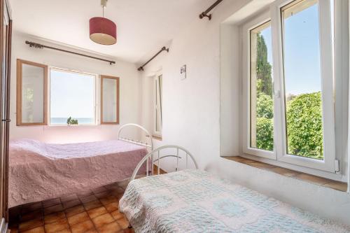 a bedroom with two beds and two windows at Maison Vacances Mer in Bages