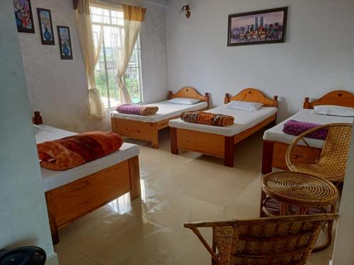 a room with four beds and a window at Vibgyor Hotel in Cherrapunji