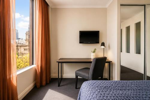 a hotel room with a desk and a window at Stylish CBD 1BR - Gym & Lounge - Next to Chinatown in Melbourne