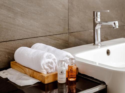 a bathroom with a sink and towels on a table at Grand Sattahip Hotel in Sattahip