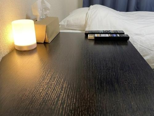 a table with two remote controls and a lamp on a bed at ドリームビレッジエンシン in Kitakami