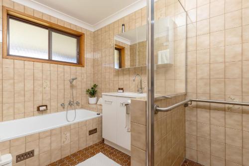 a bathroom with a tub and a sink and a shower at Byadbo in Tuncurry
