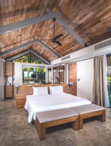 a bedroom with a large white bed and a wooden ceiling at Villa Escape Burasari in Phuket