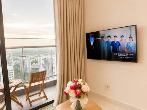 a living room with a tv and a table with flowers at 2BR-2WC-Vinhomes Grand Park-Sunset View-VincomMeGaMall-WindyHomes in Long Bình