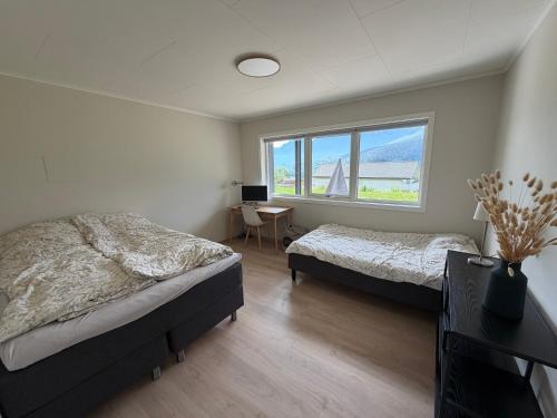 a bedroom with two beds and a desk and a window at Mountain View apartment in Isfjorden