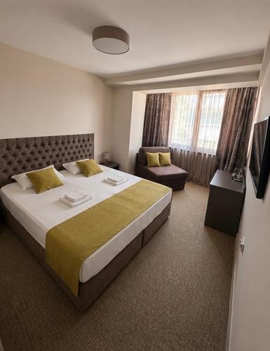 ein Hotelzimmer mit einem großen Bett und einem Stuhl in der Unterkunft Hotel Ponti in Widin