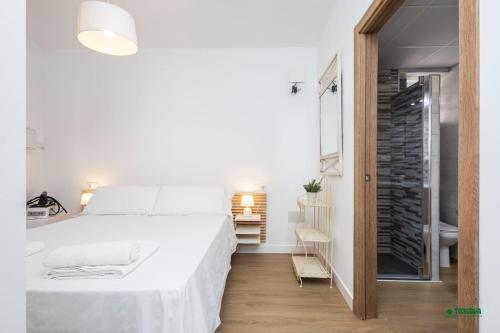 a white bedroom with a large bed and a bathroom at Habitaciones Martín in San José