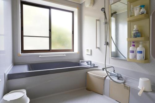a bathroom with a tub and a sink and a window at くつろ郷Kutsuro-go in Kawatana