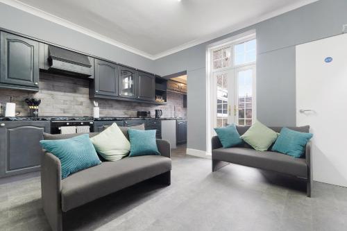 a living room with two couches and a kitchen at 4BR Mitchell Street Apartment Sleeps 6 by Stay With Us in Shield Row