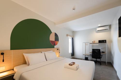 a bedroom with a white bed with a green wall at Cove Limora in Bandung