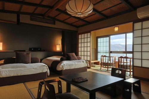 a hotel room with two beds and a table at Yuhigaura Onsen Ryotei KAI in Kyotango