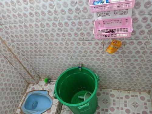 a small bathroom with a toilet and a green bucket at Bale Sasak guest house in Selaparang