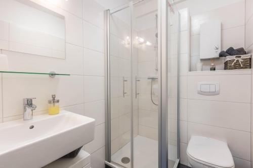 a white bathroom with a shower and a sink at Ferienwohnung Talblick in Medebach
