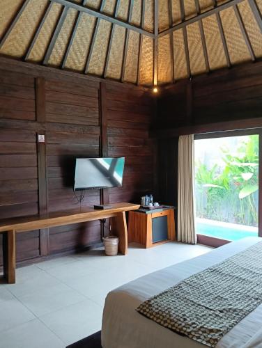a bedroom with a bed and a desk with a television at Sri Abi Ratu Villa in Sukawati
