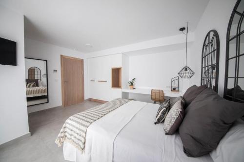 a white bedroom with a large white bed with pillows at Hostal Cervantes Playa in Garrucha