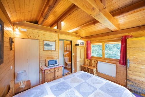 Ein Blockhütten-Schlafzimmer mit Bett und Fernseher in der Unterkunft La Datcharle in Pugny-Chatenod