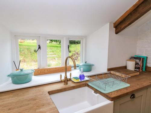 a kitchen with a sink and two windows at The Farmhouse in Langport