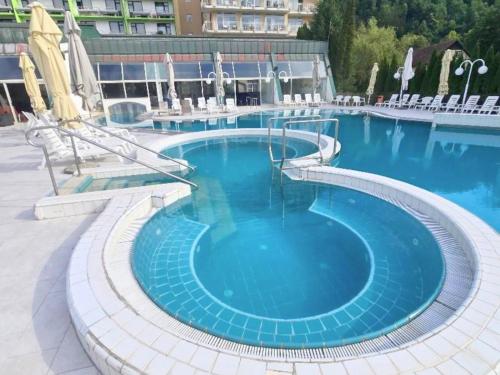 a large pool with blue water in a building at Apartment HORTENZIJA near Terme Topolšica in Topolšica