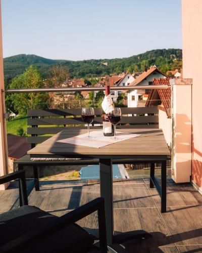 a table with two glasses of wine on a balcony at Ferienwohnung Altensteinblick in Bad Liebenstein