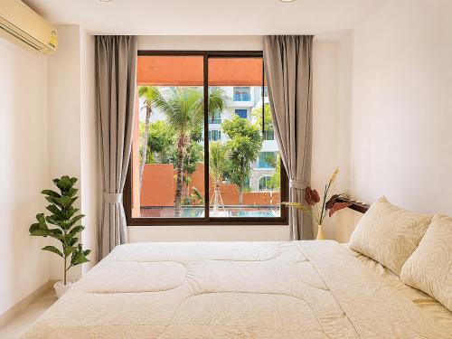 a bedroom with a bed and a large window at Las Tortugas beach front condo in Khao Tao